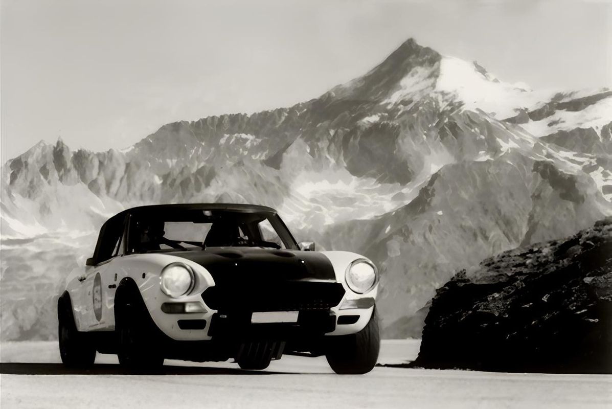 schwarz-weiß Bild eines Oldtimers vor einer Berglandschaft